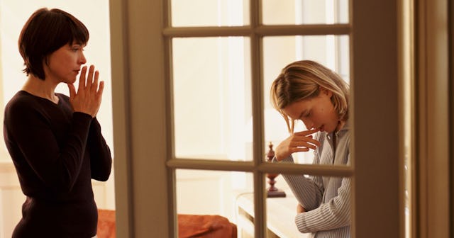 Two young women standing in an apartment feeling worried and stressed.