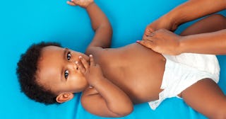 A baby with its hand covering its mouth after going #2 in its diaper