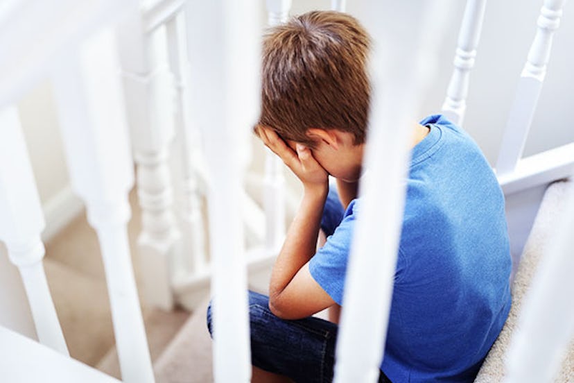  A boy in a blue shirt sitting on white stairs and crying 