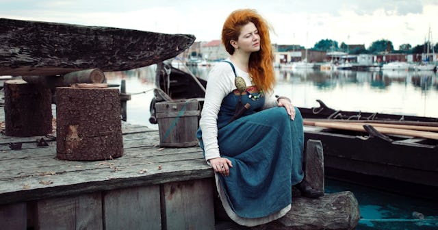 viking girl name, red haired woman viking sitting near boat