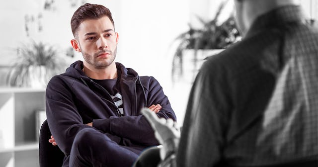 A young man wearing black clothes is having a conversation with his therapist, who betrayed him by t...