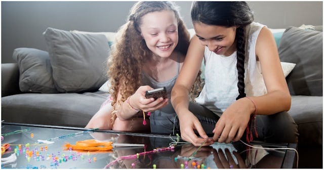Two girls sitting on the couch and curiously looking at jewelry kits