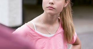 A blonde teenage girl standing with her hands at her hips 