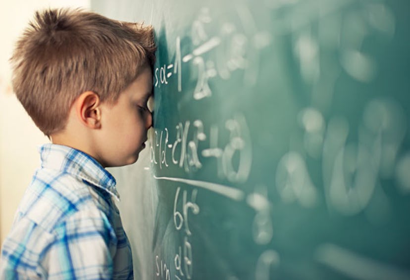 A young boy looking exhausted and disappointed, leaning his head on a writing board. 