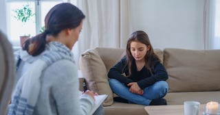 A teenage girl sitting on a couch during a session with psychologist