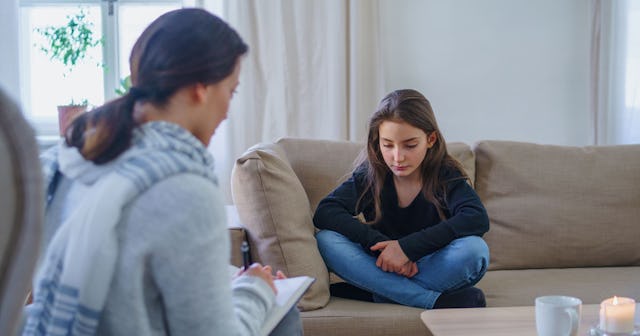 A teenage girl sitting on a couch during a session with psychologist