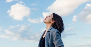 A young divorced woman with dark hair looking towards the sky on a sunny day