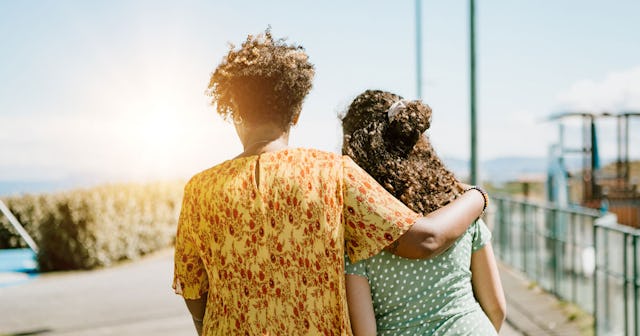 A mother walking her daughter on her way to summer school on a sunny day