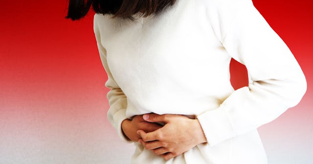 A woman dressed in a white dress holding her stomach after experiencing a very short labor 