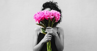 A mom in black and white holding a guilt bouquet of pink flowers, hiding her face