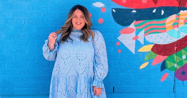 Chicago influencer Alex Stewart wearing a light blue dress and holding her hair while standing in fr...