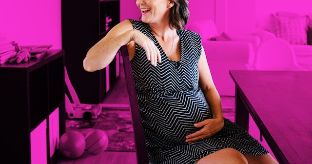 A pregnant woman in a black dress with white stripes is sitting at the table with a pink color-filte...