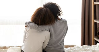 Two sisters sitting on their bed and hugging 