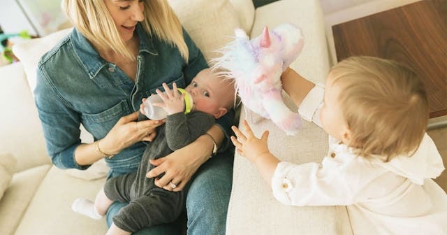 Mom breastfeeding her baby while her toddler is playing around