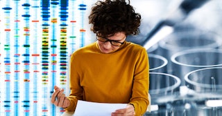 Woman in an orange long-sleeved shirt wearing black glasses reading the results of a genetic test 