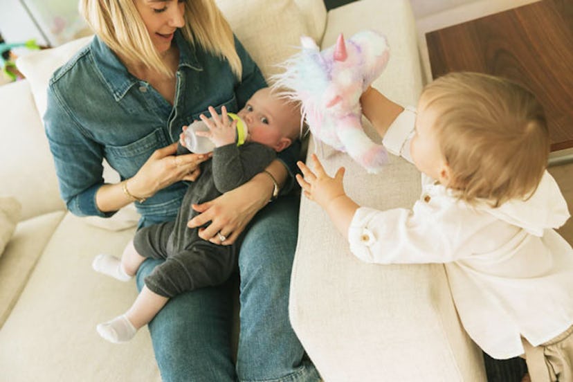 Mom breastfeeding her baby while her toddler is watching them 