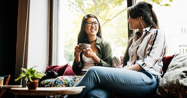 A woman smiling while having a conversation and a coffee with her new friend
