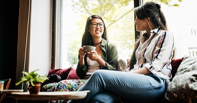 A woman smiling while having a conversation and a coffee with her new friend 