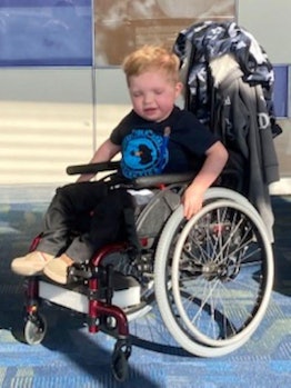 Five-year-old Cameron pushing his wheelchair with closed eyes during a day