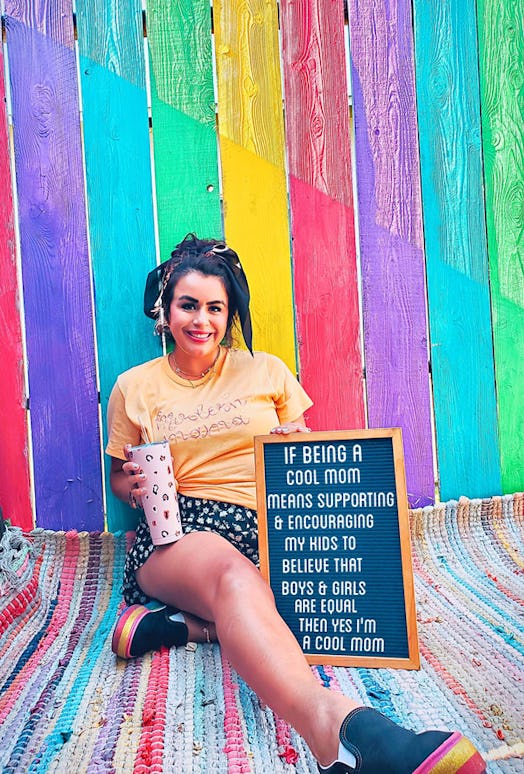 A social media influencer holding a chalkboard with text about encouraging her boys and girls to be ...