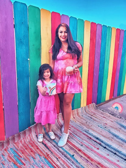 A social media influencer and her little girl posing for a picture in pink dresses.