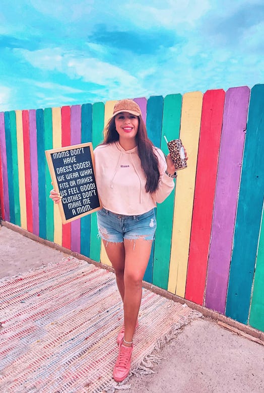 A social media influencer holding a tiger-print cup and a chalkboard.
