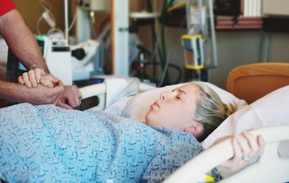 Husband holding his wife's hand while she is in a hospital bed