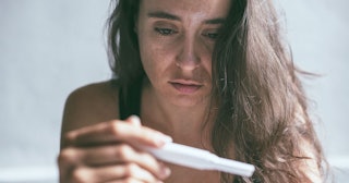 A sad woman looking at her pregnancy test.