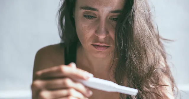 A sad woman looking at her pregnancy test.