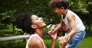 A mother holding hands with her son while they are both laughing in a park