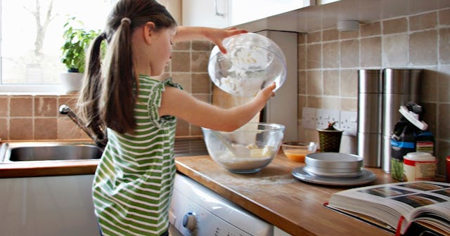 A little girl in a green striped shirt preparing food