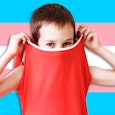 Child covering his face with his shirt with a transgender flag in the background