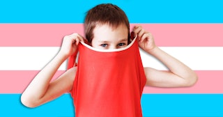 Child covering his face with his shirt with a transgender flag in the background