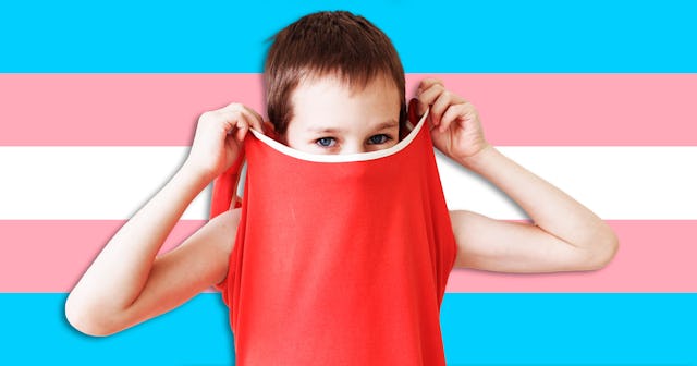 Child covering his face with his shirt with a transgender flag in the background