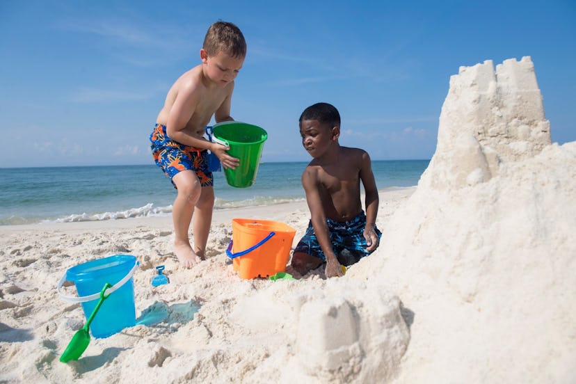 Two children making a sandcastle on the beach.