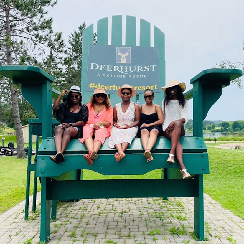 Tarila Morrone and her four friends on a girls' trip sitting on a large green bench