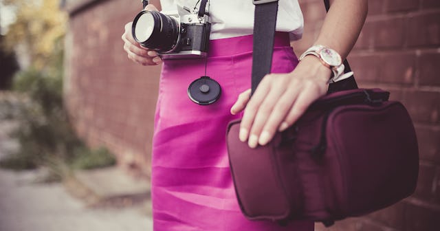 A woman carrying a purple crossbody camera bag on her shoulder 