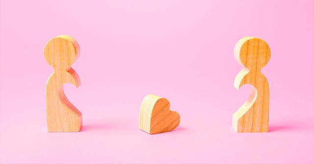 Two wooden figurines representing friendship, with a wooden heart positioned between them.