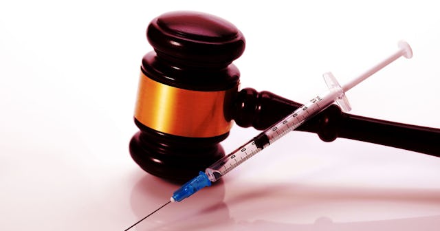 COVID Vaccine standing next to a gavel on a white background