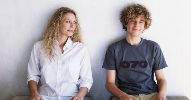 Mom and her teen son sitting leaned against the wall