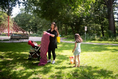 A mother getting ready for a picnic with her two kids at a park