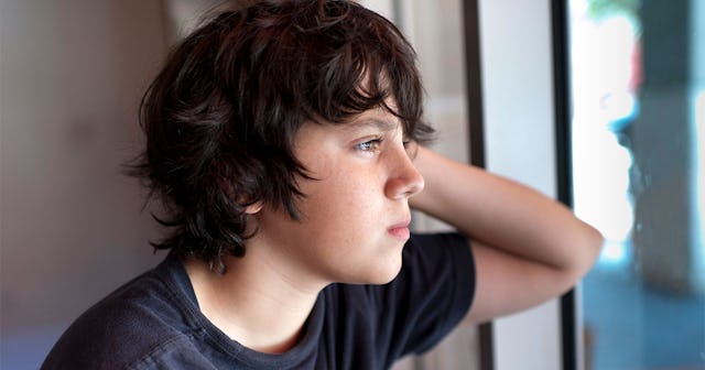 Emotionally unstable terrn in a black shirt leaning on a window with his elbow, looking into the dis...