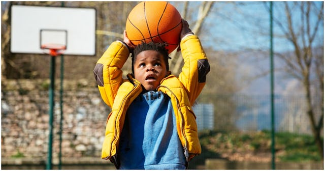 A boy playing with a basketball like an athlete 