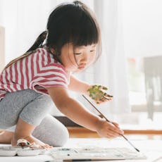 Little girl painting a craft with green paint.