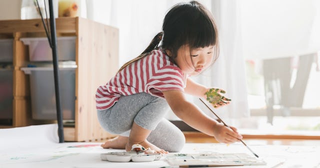Little girl painting a craft with green paint.