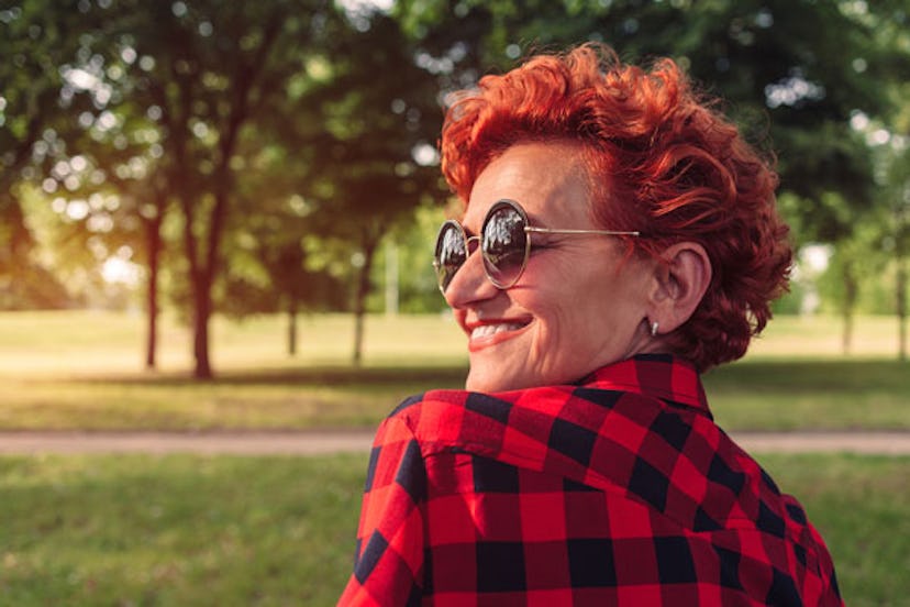 Older lady with red hair, wearing sunglasses and looking over her shoulder