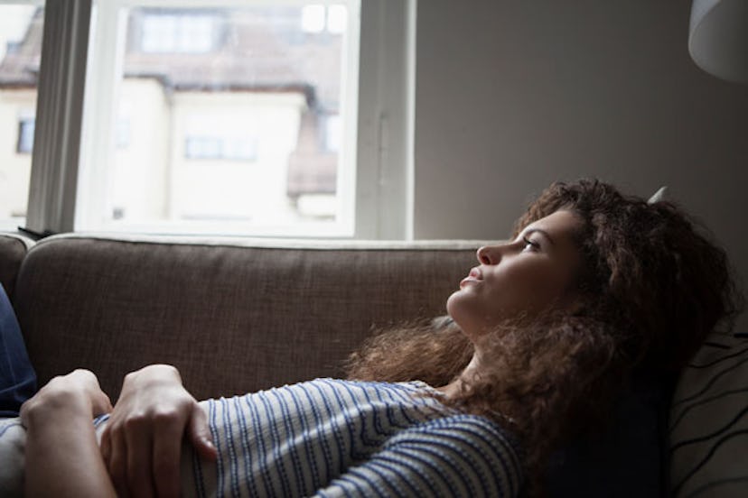  A curly woman lying on the couch in a striped shirt