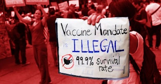 People protesting and a sign in focus that says vaccine mandates are violating rights