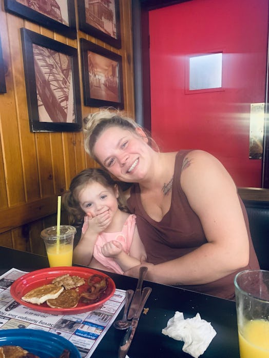 Mother and daughter hugging and having breakfast and juice at a diner