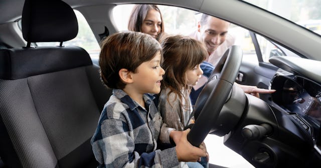 Happy family looking at new car — car nicknames.